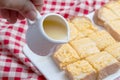 Pouring condensed milk on toasts with butter