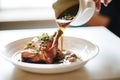 pouring coq au vin from pot into a white serving dish