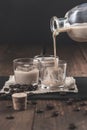 Pouring  Cream coffee liqueur in glasses with ice, surrounded by coffee beans on a dark wooden background Royalty Free Stock Photo