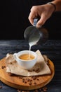 Pouring cream to cup of coffee. A stream of milk pours into the cup