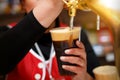 Pouring dark beer to plastic glass from beer tap. Royalty Free Stock Photo