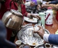 Pouring dark coffee from a communal pot into cups in Ethiopia