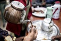 Pouring dark coffee from a communal pot into cups in Ethiopia