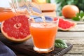 Pouring delicious grapefruit juice into glass on wooden table