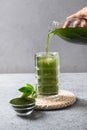 Pouring detox healthy Chlorella beverage in glass.