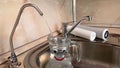 Pouring filtered water into happy glass pitcher from water filter. Closeup of jug, sink and faucet. Drinkable water Royalty Free Stock Photo
