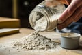 Pouring fine powder from a container onto a surface is part of a crafting or construction process done by hand Royalty Free Stock Photo