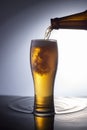 Pouring foamy beer from bottle into glass on water advertising photo