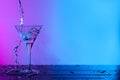 Pouring fresh martini into glass on table in neon lights, space for text Royalty Free Stock Photo