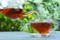 Pouring fresh mint tea into cup on blue wooden table, closeup Royalty Free Stock Photo