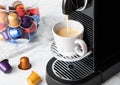 Pouring fresh morning coffee with espresso machine and capsules pods on white marble background Royalty Free Stock Photo