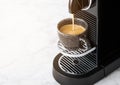 Pouring fresh morning coffee from home espresso machine to black cup on white background Royalty Free Stock Photo