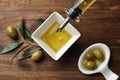 Pouring fresh olive oil into bowl on table,