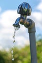 Pouring fresh water  from the metal tap with blurred nature and blue cloudy sky background Royalty Free Stock Photo