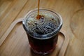 Pouring freshly brewed black pour over filter coffee into glass on wooden table, close-up Royalty Free Stock Photo
