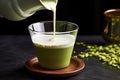 pouring frothed milk into a cup of matcha