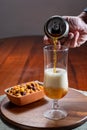 Pouring of German wheat beer is glass and bowl with party mix nuts Royalty Free Stock Photo