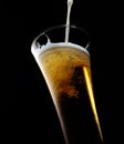 Pouring into a glass of cold foamy beer on a black background