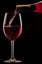Pouring a glass of red wine on black background Royalty Free Stock Photo
