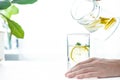 Pouring a glass of water with lemon, ice and mint on a white table Royalty Free Stock Photo