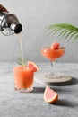Pouring grapefruit cocktail in glass. Vertical format
