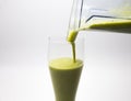 Pouring green smoothie into glass