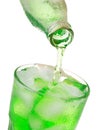 Pouring green soda into glass with ice from bottle