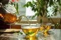 Pouring green tea into glass cup with saucer and leaves on wooden table Royalty Free Stock Photo