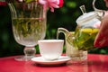 Pouring green tea from glass teapot in white cup Royalty Free Stock Photo