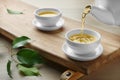 Pouring green tea into white cup on wooden table, closeup Royalty Free Stock Photo