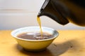 Pouring herbal tea from an enamel pot to a bowl