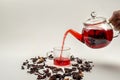 Pouring hibiscus tea from a glass teapot. Scattered dry hibiscus leaves.