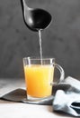 Pouring Homemade Beef Bone Broth in Glasses on a gray concrete background