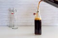 Pouring homemade cold brew coffee from glass jar to glass bottle Royalty Free Stock Photo