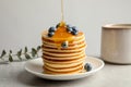 Pouring honey onto tasty pancakes with berries Royalty Free Stock Photo