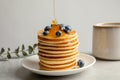 Pouring honey onto tasty pancakes with berries Royalty Free Stock Photo