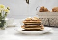 Pouring honey onto tasty pancakes on wooden table, closeup Royalty Free Stock Photo