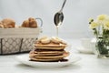 Pouring honey onto tasty pancakes on wooden table, closeup Royalty Free Stock Photo