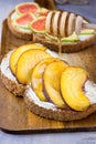 Pouring honey with wooden dipper on toast with whole grain bran rye bread slice with cream cheese, peaches, figs. Royalty Free Stock Photo