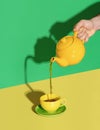 Pouring mint tea from a teapot in a cup, minimalist on a vibrant background Royalty Free Stock Photo