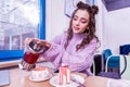 Concentrated dark-haired girl adding more tea into cup