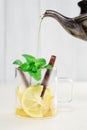 Pouring tea from a teapot into a cup with lemon, cinnamon and mint Royalty Free Stock Photo