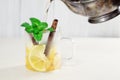 Pouring tea from a teapot into a cup with lemon, cinnamon and mint Royalty Free Stock Photo