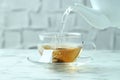 Pouring hot water into cup with tea bag on light marble table, closeup Royalty Free Stock Photo
