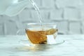 Pouring hot water into cup with tea bag on light marble table, closeup Royalty Free Stock Photo