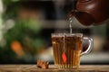 Pouring hot water into glass cup with tea bag at wooden table against blurred background, space for text Royalty Free Stock Photo