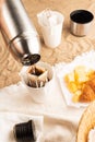 Pouring hot water through trendy convenient paper drip coffee bag into paper cup outdoors. Royalty Free Stock Photo