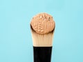 Pouring liquid beige makeup foundation on a brush makeup