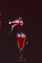 Pouring liquor from decanter isolated on dark cherry background. Tasting of an elite drink. Royalty Free Stock Photo