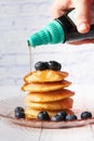 pouring maple syrup on pancakes with fresh berries on plate Royalty Free Stock Photo